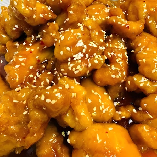 Close-up of Weng's Kitchen's orange chicken, glistening with sauce and sprinkled with sesame seeds.